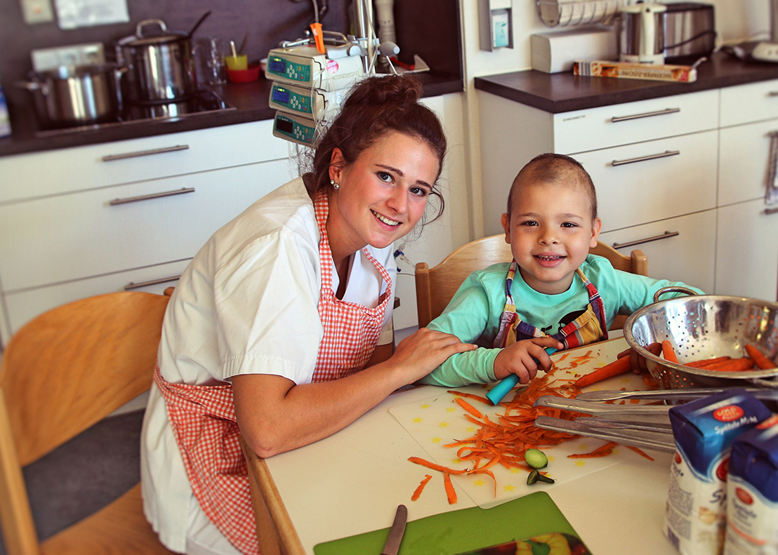 betreuerin mit krebskrankem kind beim kochen auf station