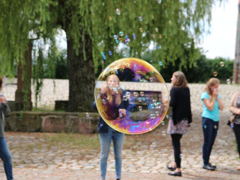 Seifenblase in der Natur mit Mensch im Hintergrund