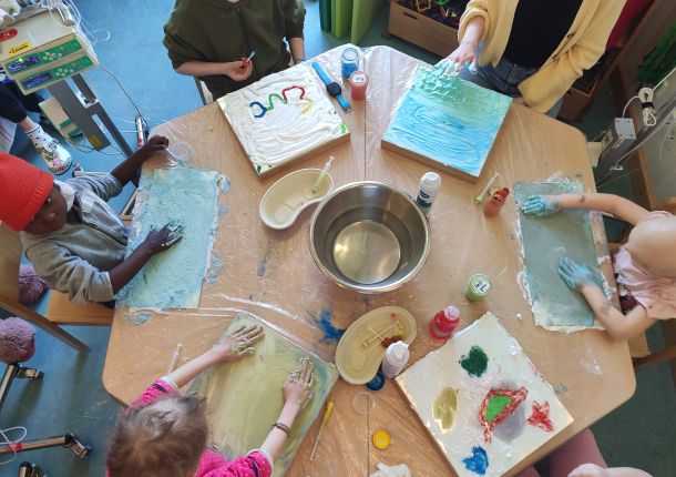 krebskranke Kinder, die am Tisch mit Handfarben malen