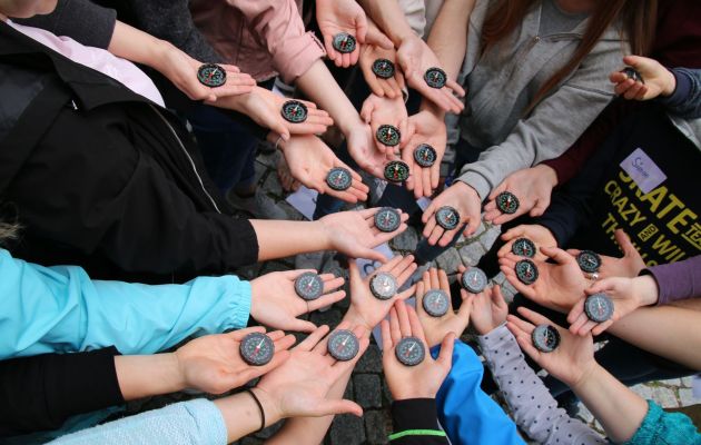 Viele Kinderhände, die einen Kompass auf der Hand liegen haben, um Trauer zu verarbeiten